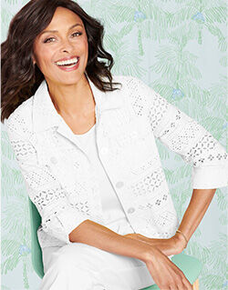 smiling model wearing white eyelet jacket with solid white tee underneath, white pants