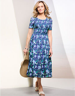 woman wearing a patterned blue dress, holding a tan hat