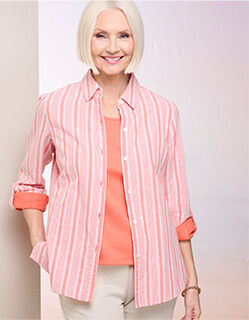 model wearing unbuttoned and open pink and white striped shirt with pale salmon colored tee shirt underneath