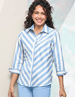 model wearing white and blue stripe blouse with stripes on bias, and solid light blue pants