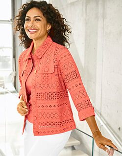 woman wearing orange eyelet blouse with matching solid orange tee shirt underneath and white pants