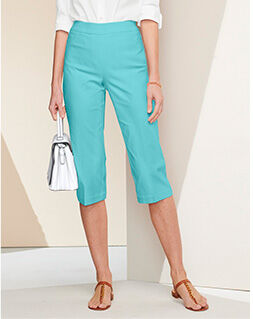 waist-down view of model wearing light aqua capris, tan sandals, holding a white pocketbook