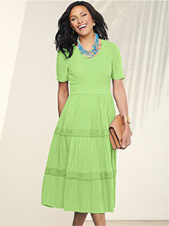 woman wearing green dress holding beige purse
