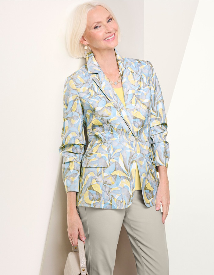 woman wearing geometric patterned jacket with pale blue and yellow design, light beige pants