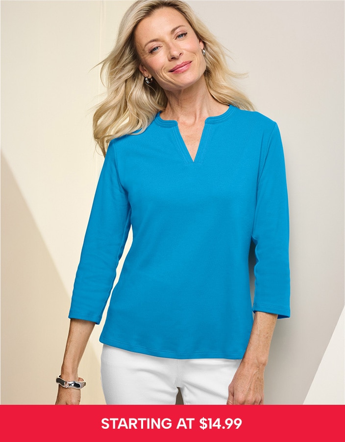 model wearing blue top and white pants smiling into the camera