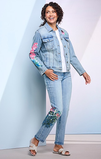 model wearing jean jacket with embroidery on sleeve, and light blue jeans with embroidered pattern on leg