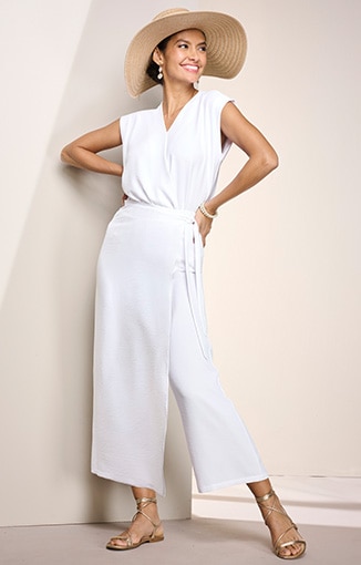 model wearing white jumpsuit, and wide-brim hat